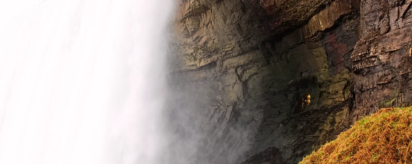 Mist rising beside the rock face at the base of the falls