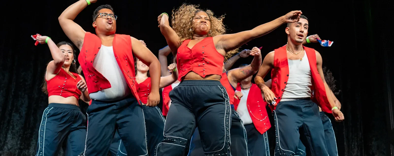 Dancers from Araguacu Latin Dance Co performing in red vests on stage